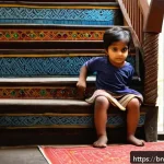 Home 18 아기 안전 가드 설치법 - A cozy Bengali home interior featuring a toddler safely playing near a sturdy, rust-proof metal safe...